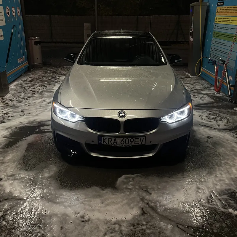 BMW z włączonymi reflektorami na myjni nocą - życie doradców finansowych Penthouse Office po pracy
